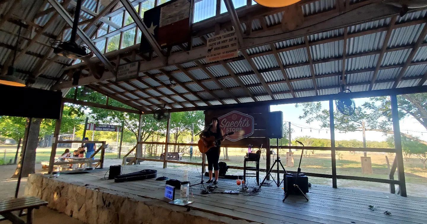 A man is playing a guitar on a stage in a pavilion.