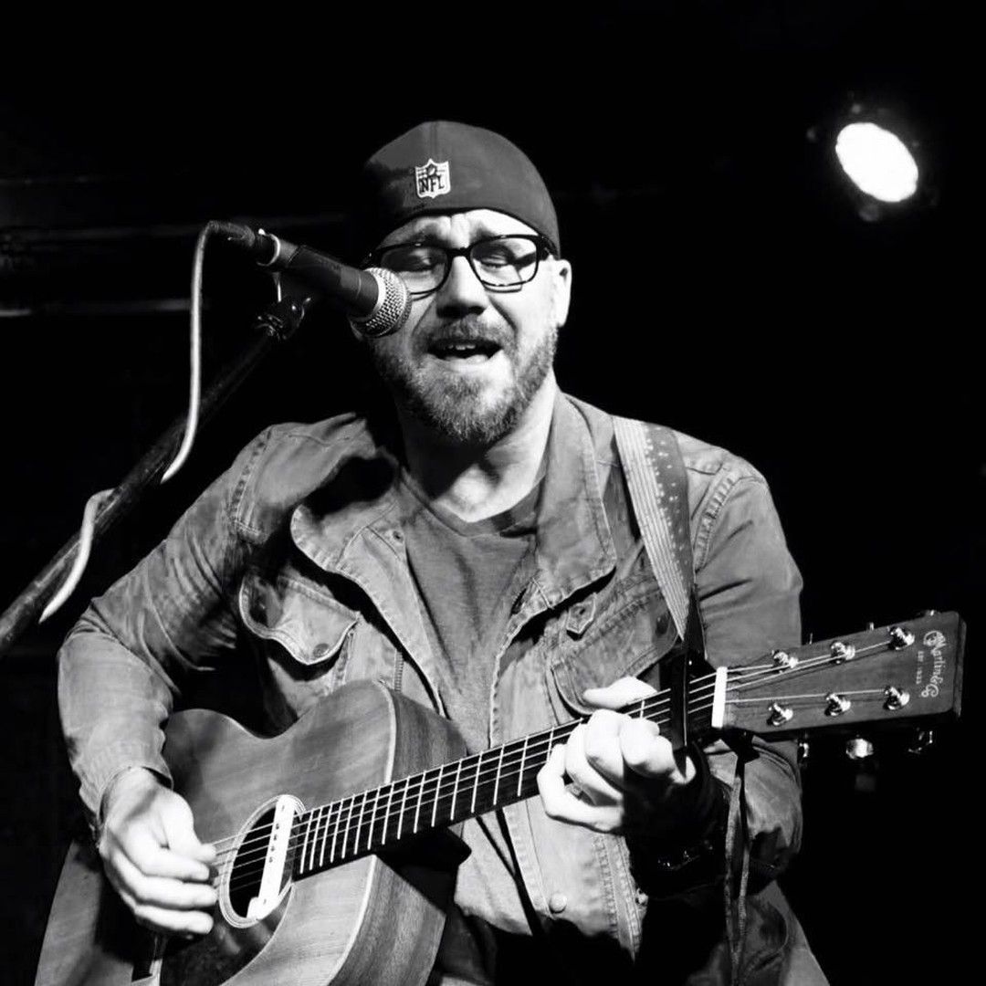 A man is singing into a microphone while playing a guitar.