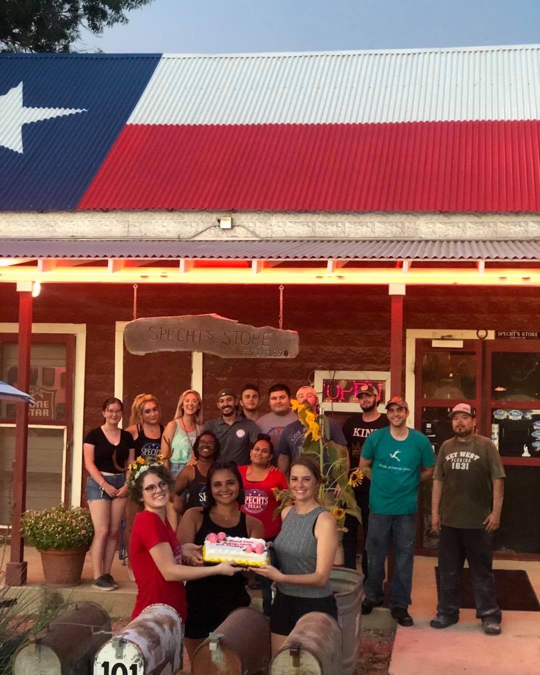 A group of people standing in front of a building with a Texas flag on it.