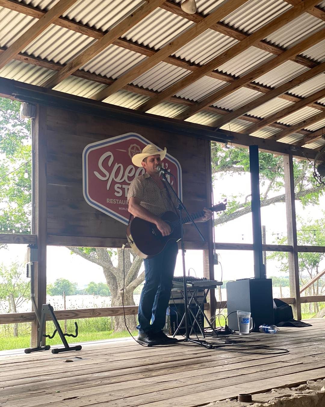 A man is playing a guitar and singing into a microphone on a stage.