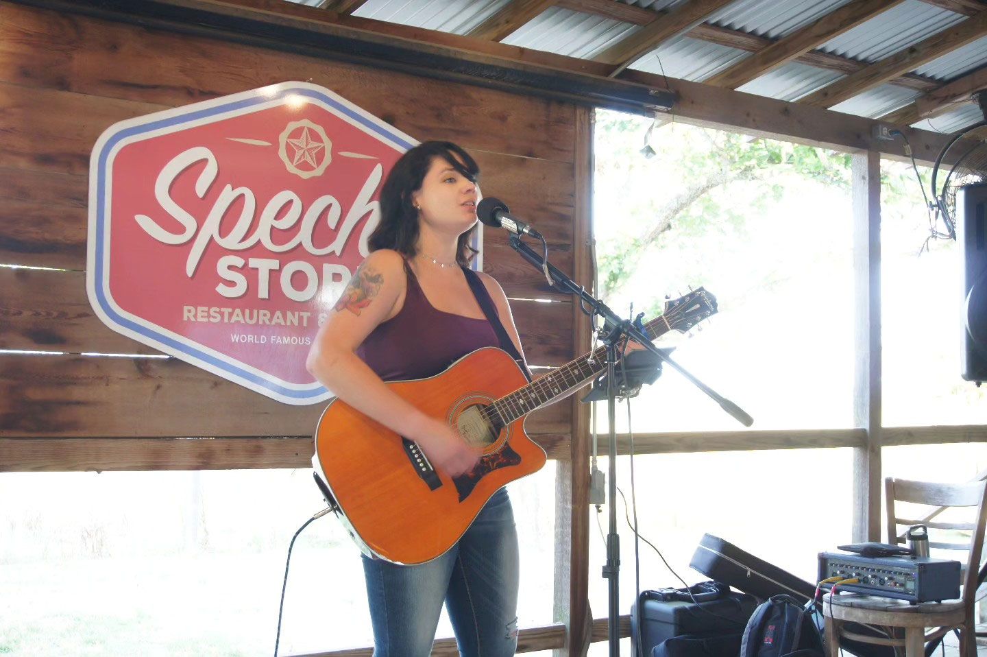 A woman is singing into a microphone while playing a guitar.