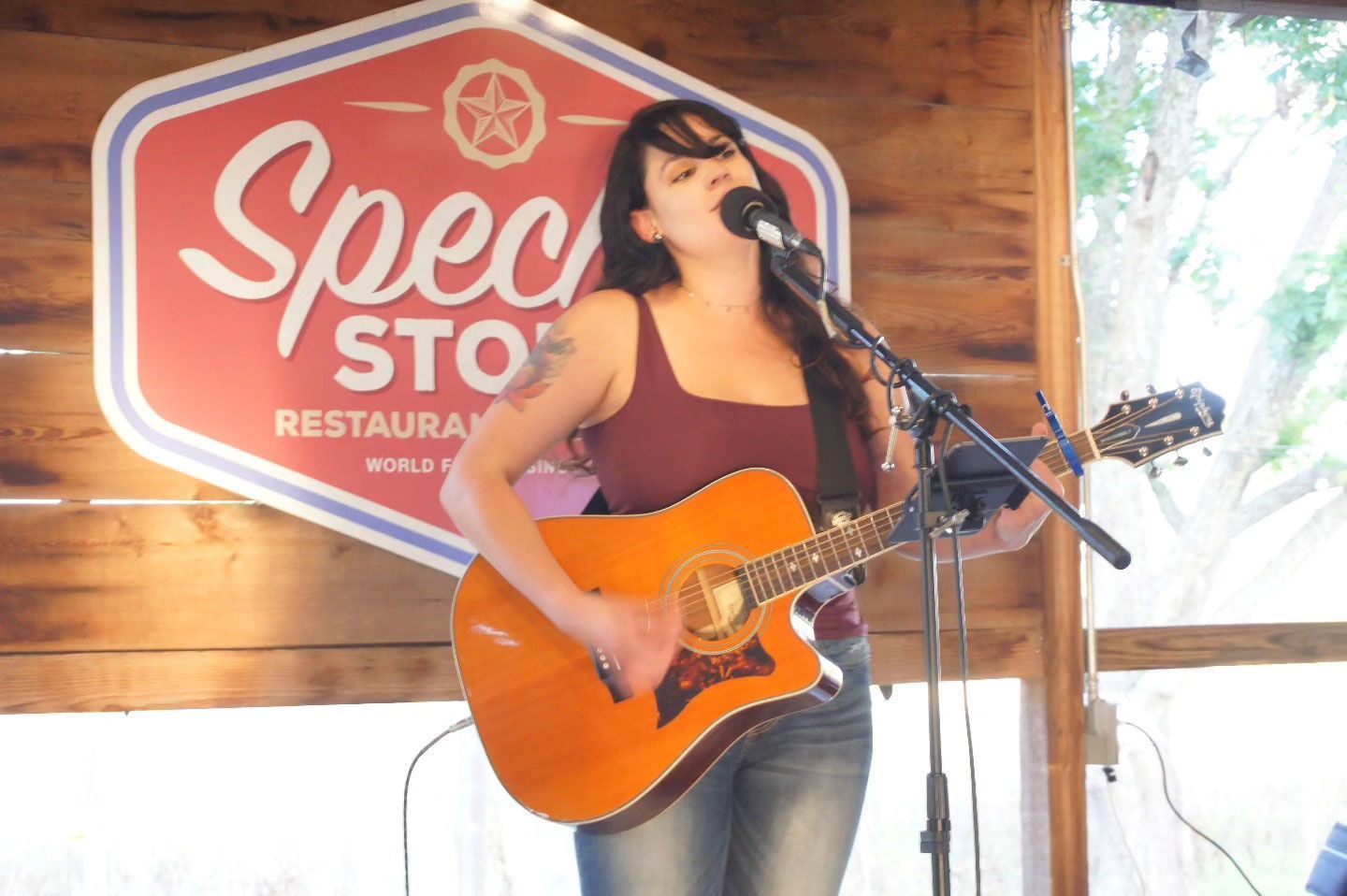 A woman is singing into a microphone while playing a guitar.