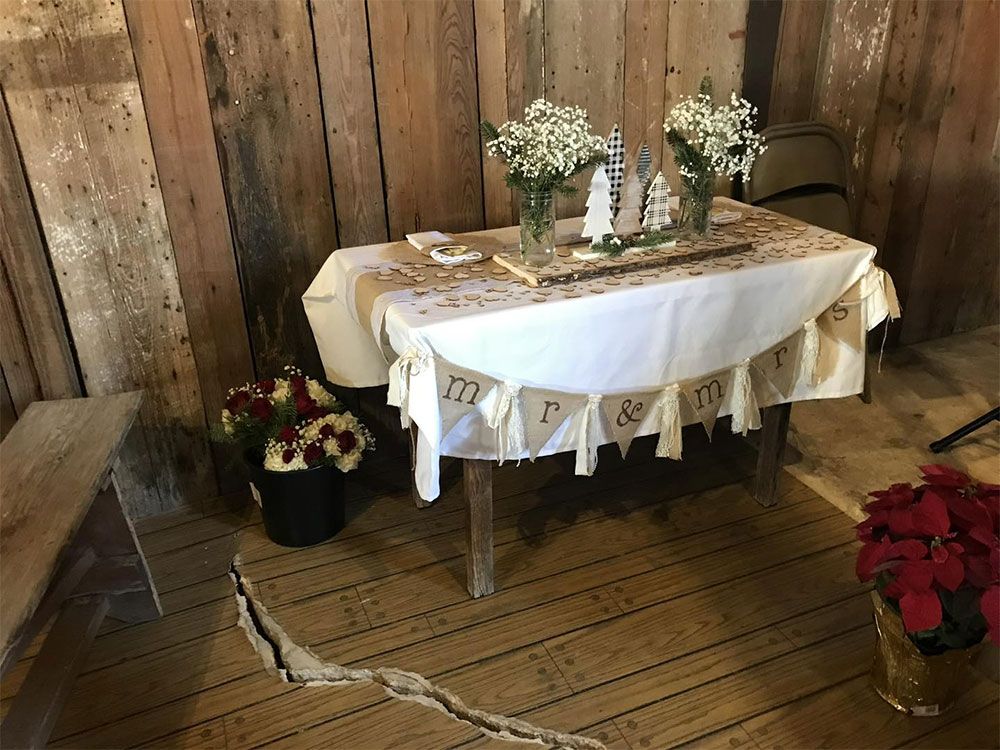 A table with a white table cloth and flowers on it is sitting on a wooden floor.