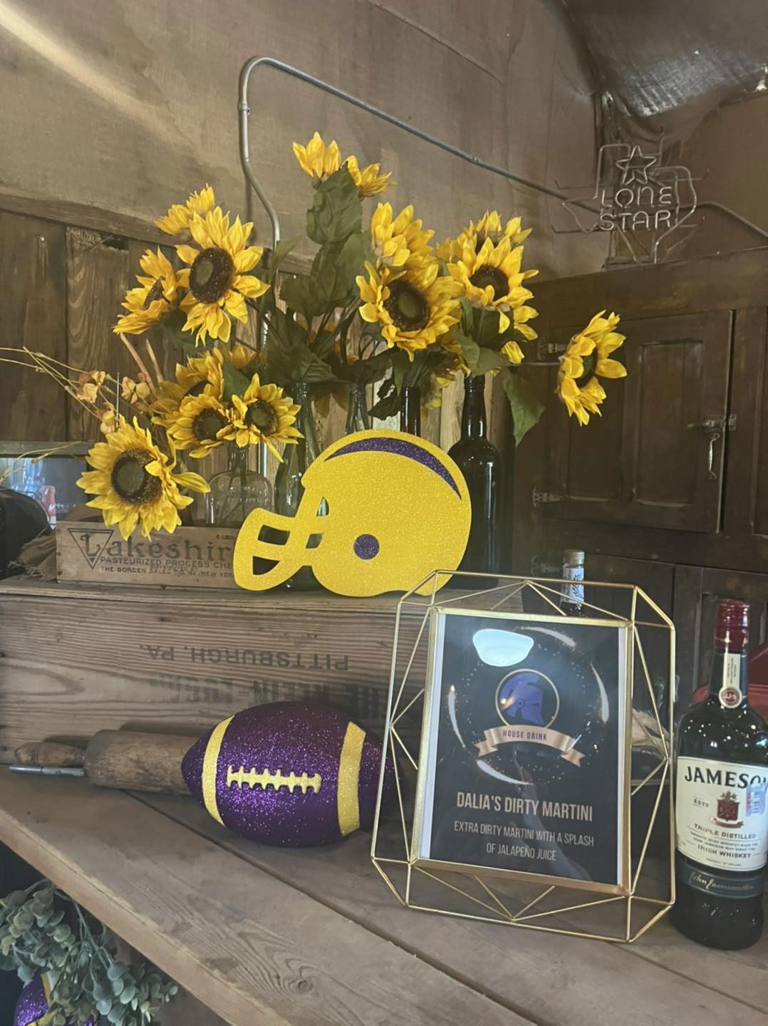 A table with sunflowers a football and a bottle of Jameson.