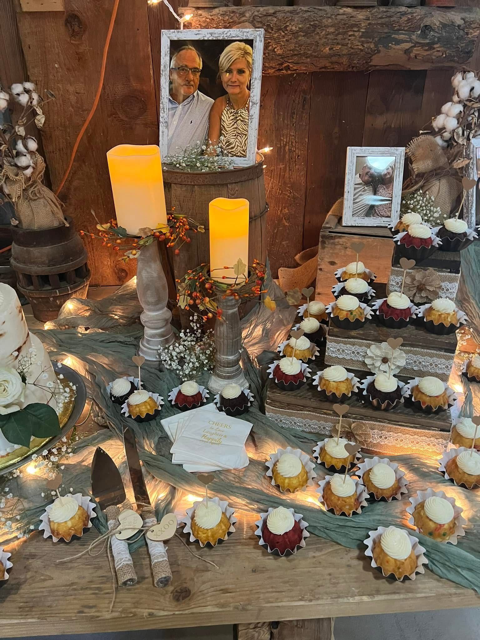 A wooden table topped with cupcakes, candles, and pictures of a bride and groom.