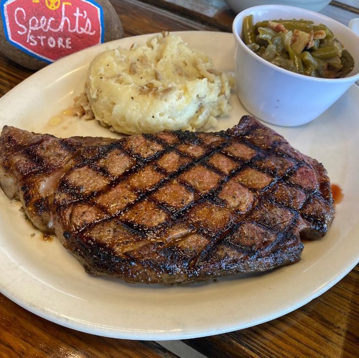 A white plate topped with a steak and mashed potatoes.
