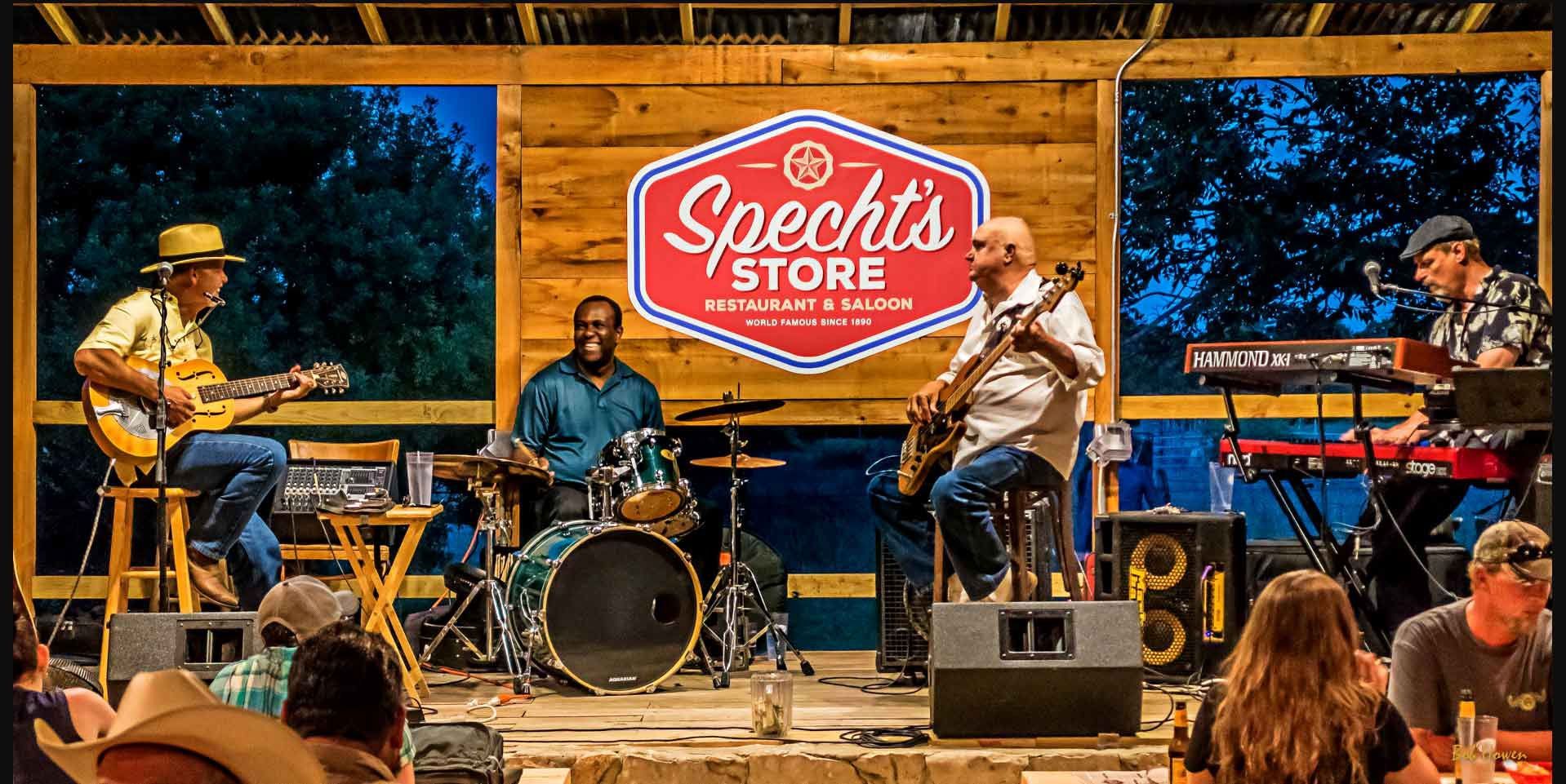 A group of men are playing instruments on a stage in front of a sign that says speech 's store.