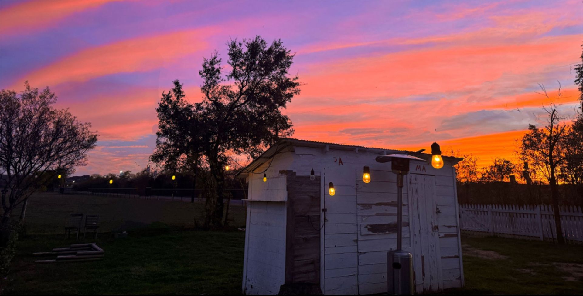 A white shed with a sunset in the background.