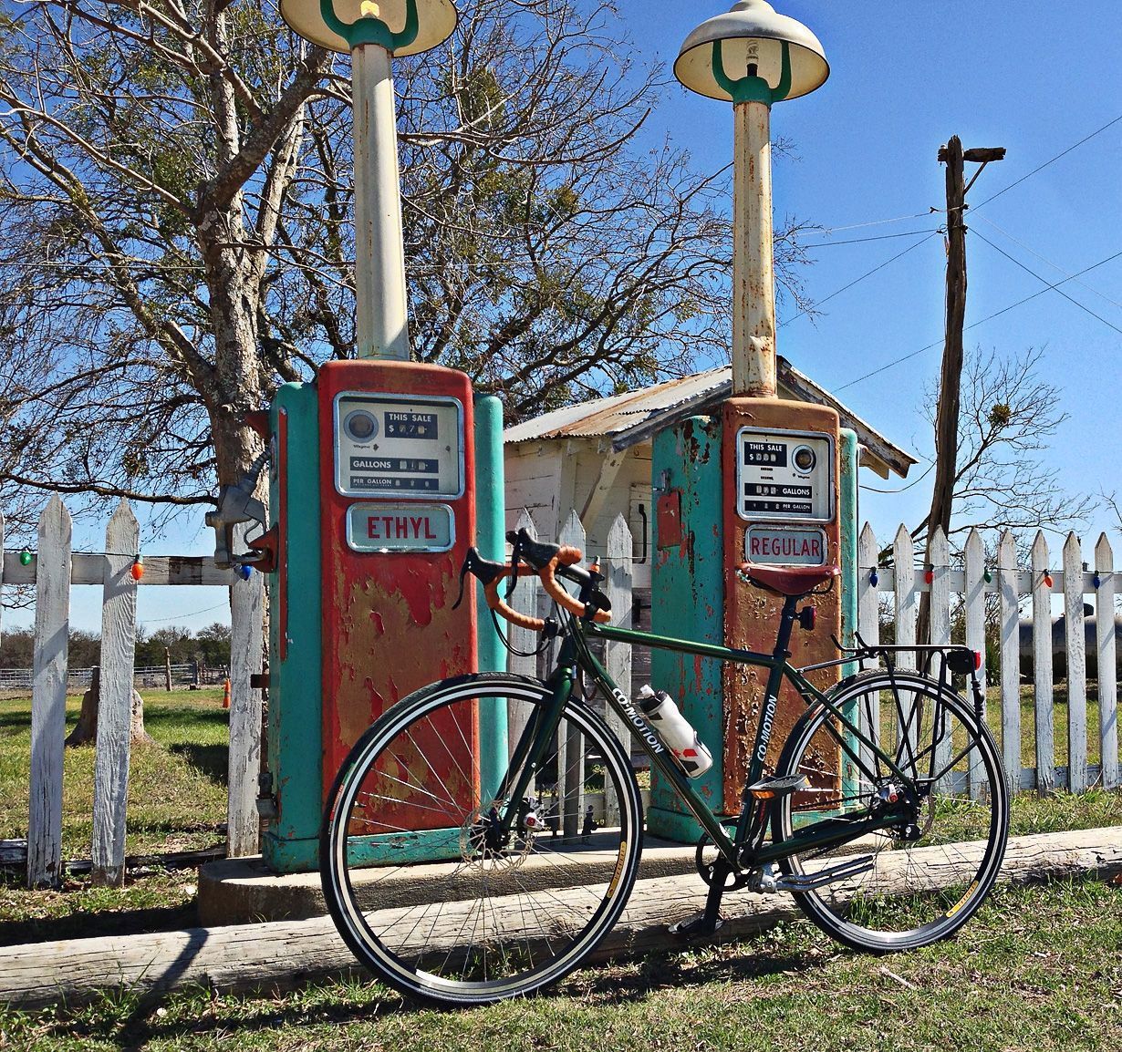 A bicycle is parked in front of a gas pump that says ethyl.
