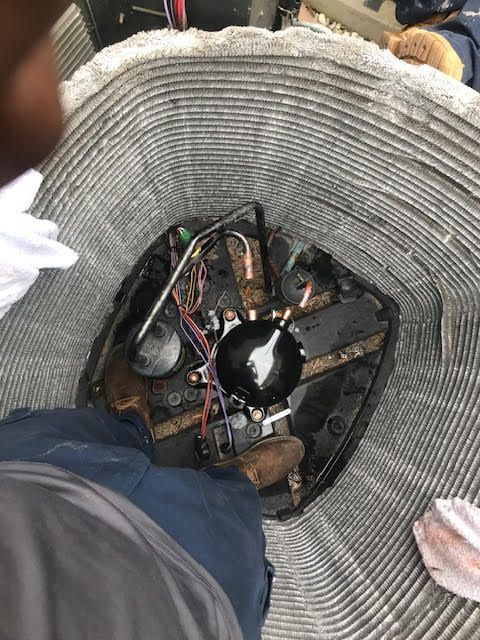 Inside a woven basket, a person looks down into a tangle of wires and a round device on the floor