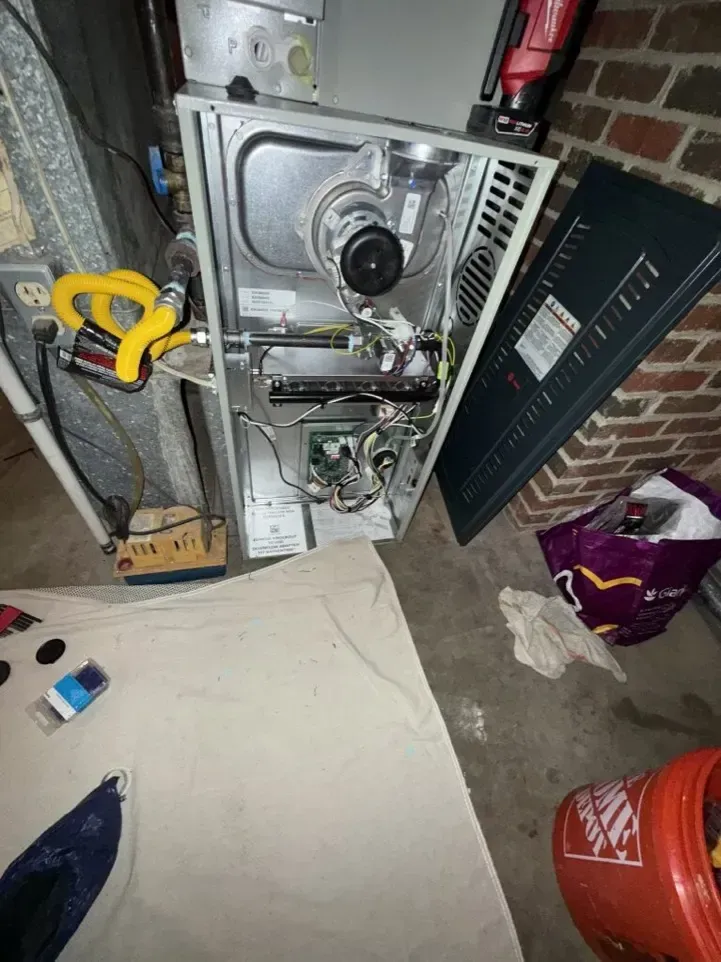 Utility furnace and HVAC unit in a cluttered basement corner with tools and bags nearby