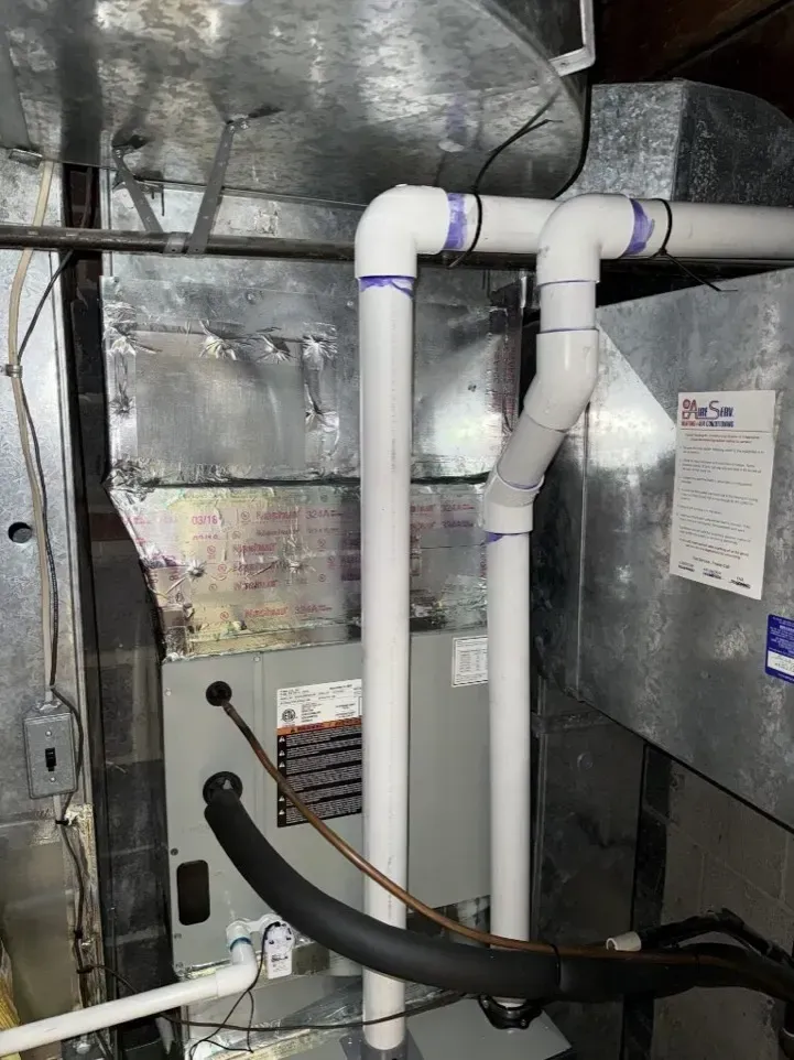 HVAC closet with insulated ducts, white PVC pipes, and a gray utility panel on foil-backed walls