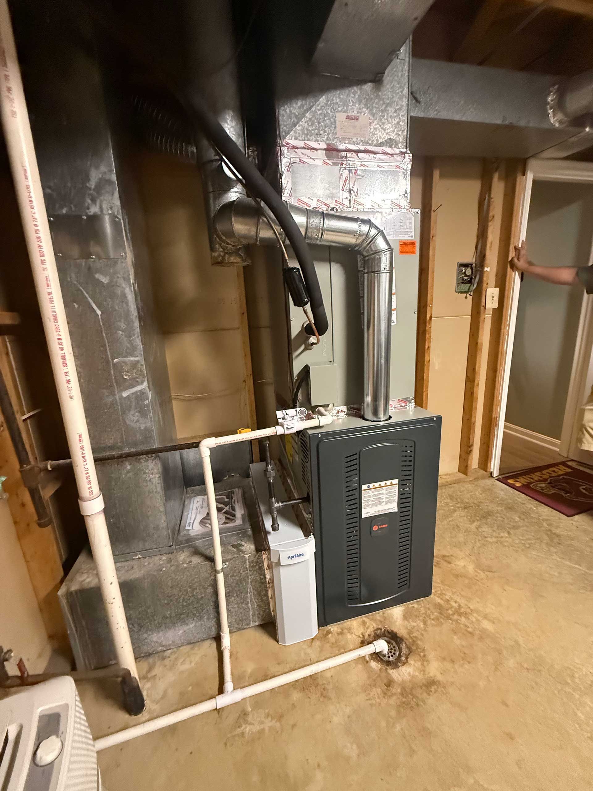 Utility room with exposed pipes, a gray electrical panel, and white PVC piping on a rough concrete floor