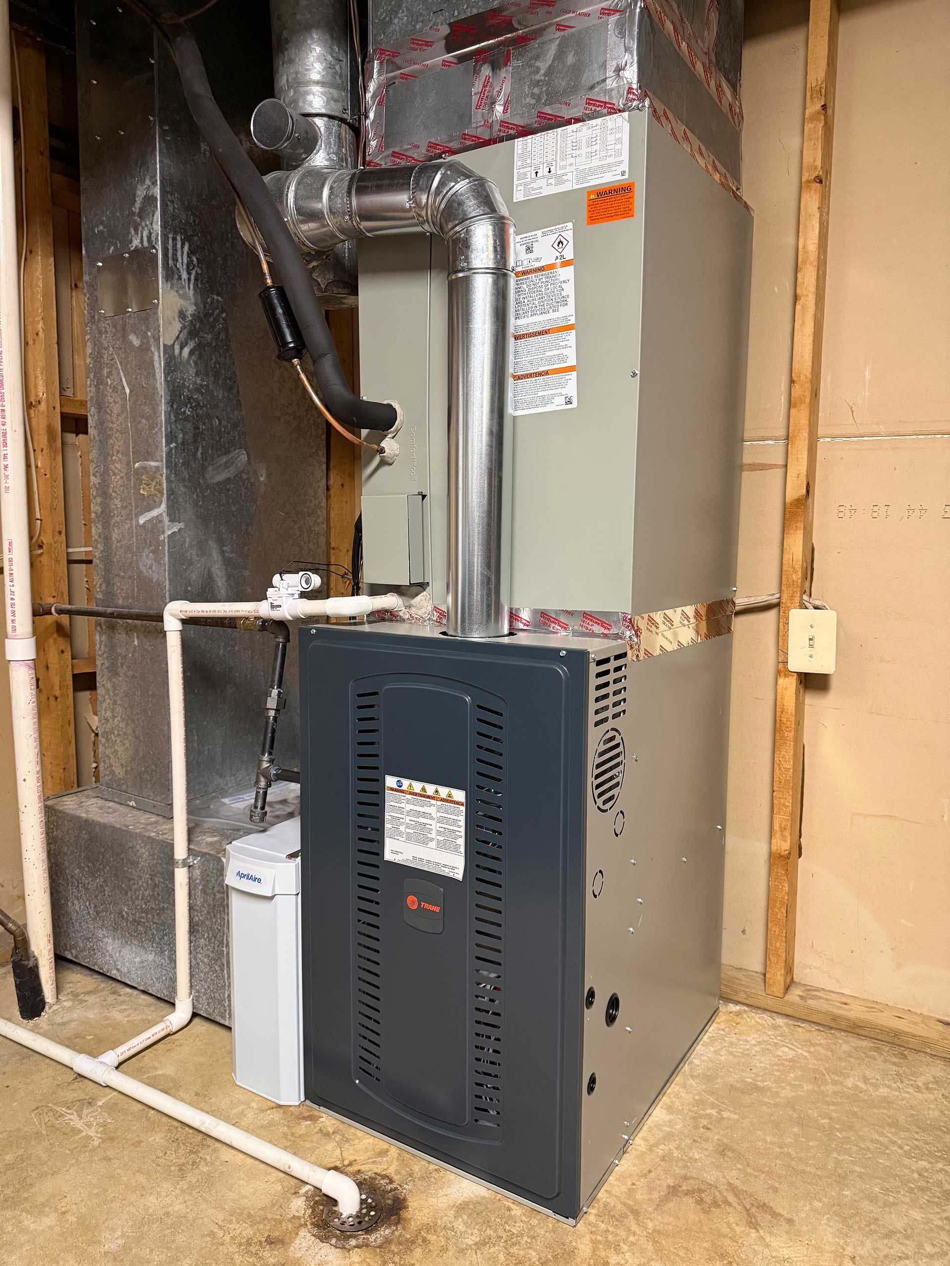 Furnace and HVAC equipment in a basement utility room with exposed ducts and piping
