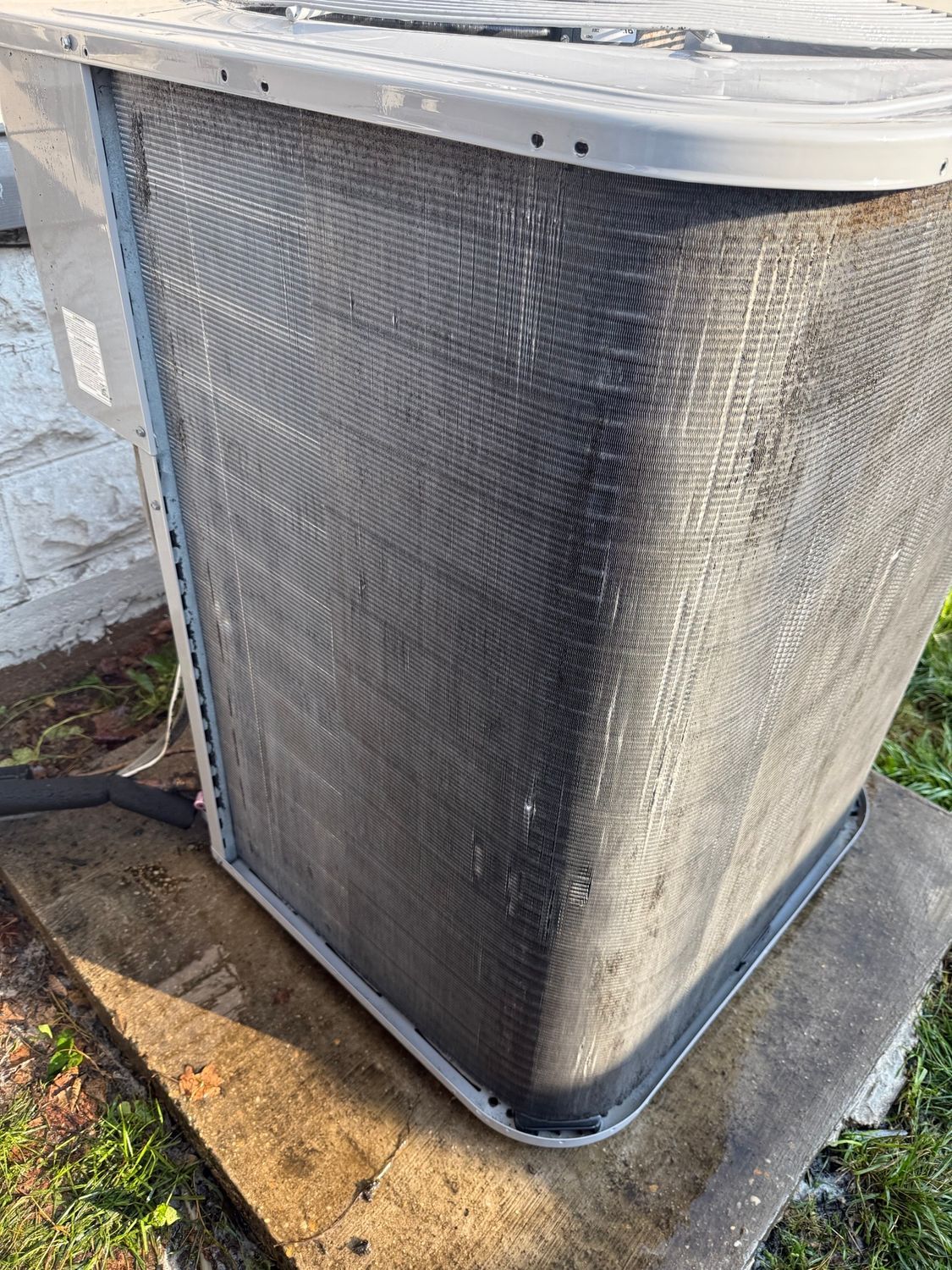 Outdoor HVAC unit with a dirty, weathered coil cover on a concrete pad