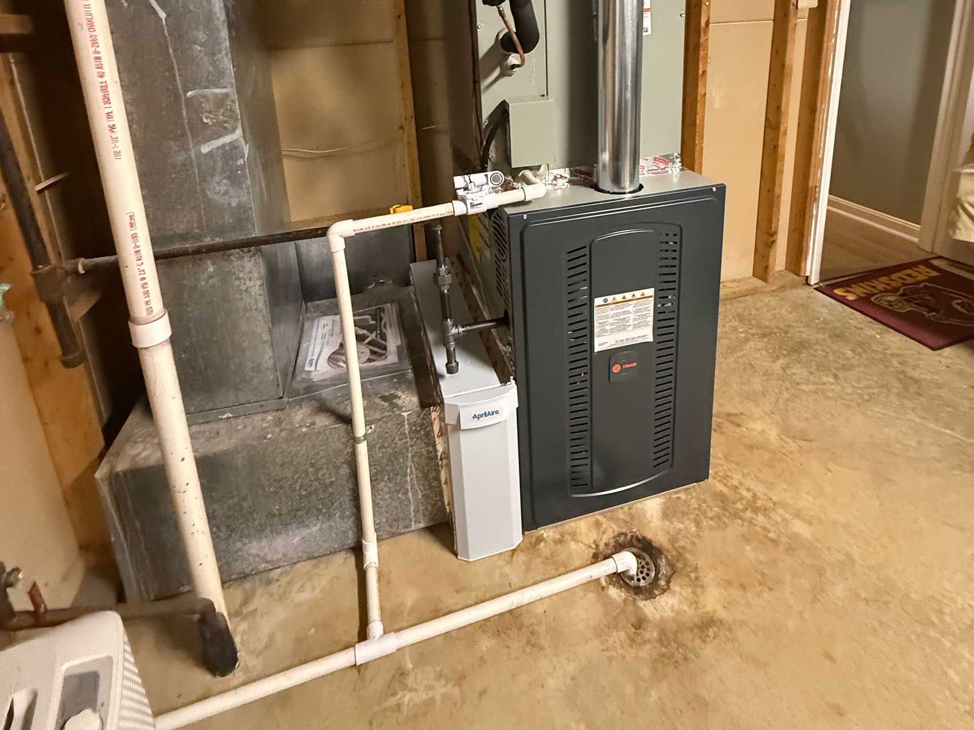 Basement utility area with furnace, white pipes, and concrete floor with floor drain