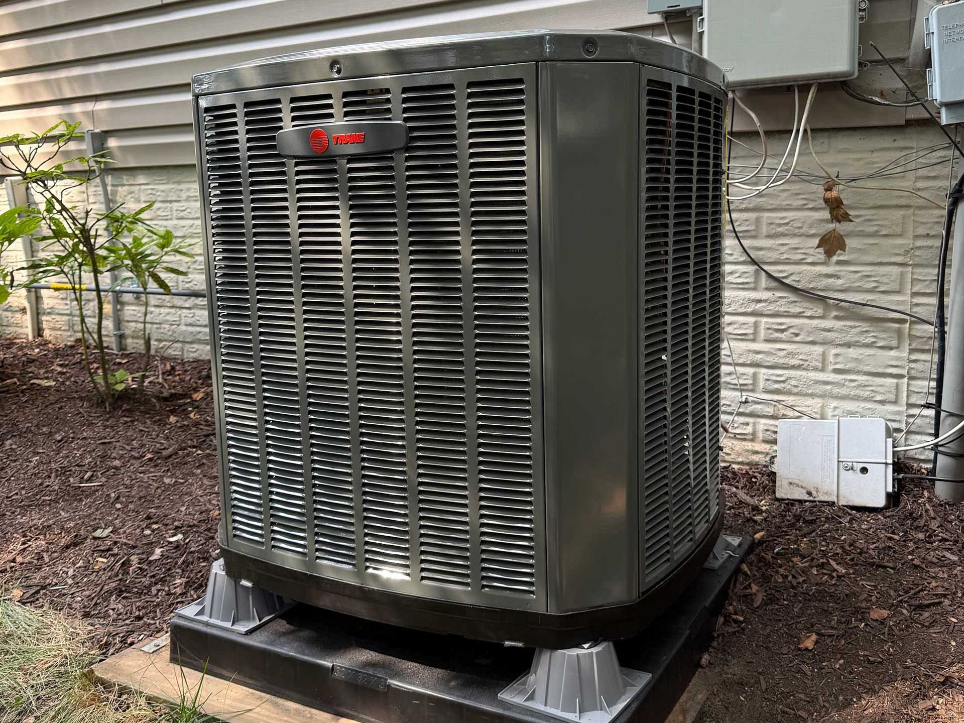 Large gray outdoor HVAC unit beside a house on a concrete pad