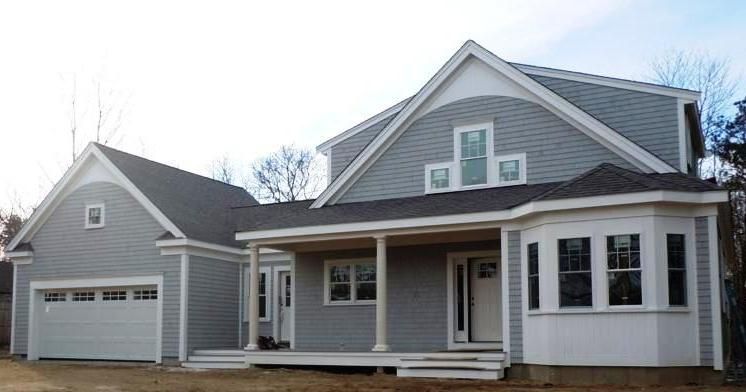A large gray and white house with a garage and porch.