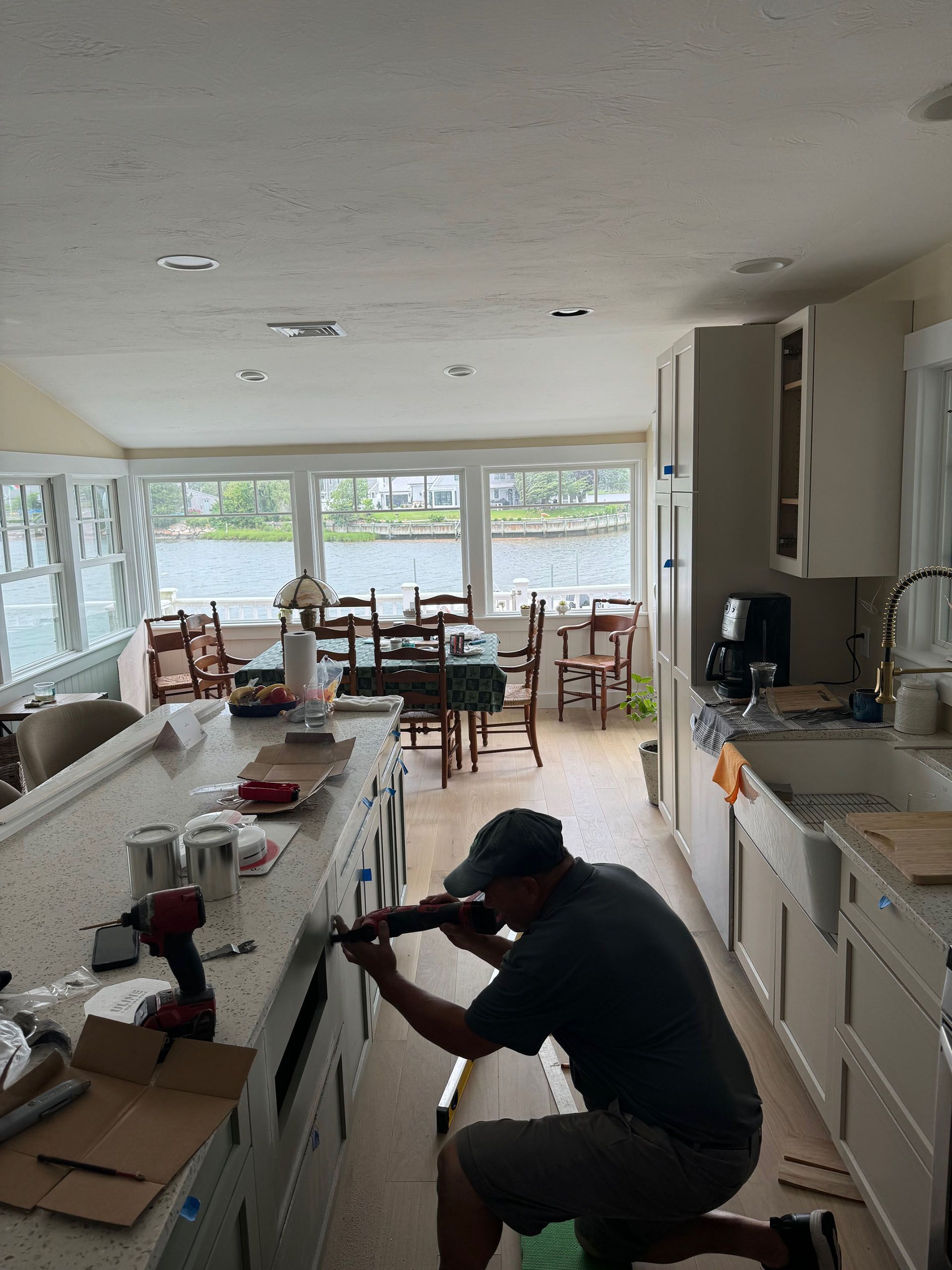 A man is working on a kitchen counter with a drill.
