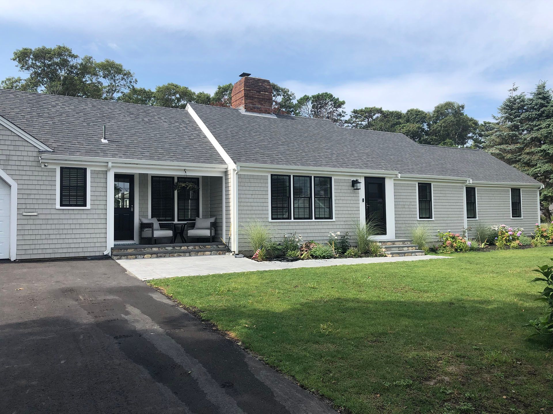 A white house with a gray roof and a driveway