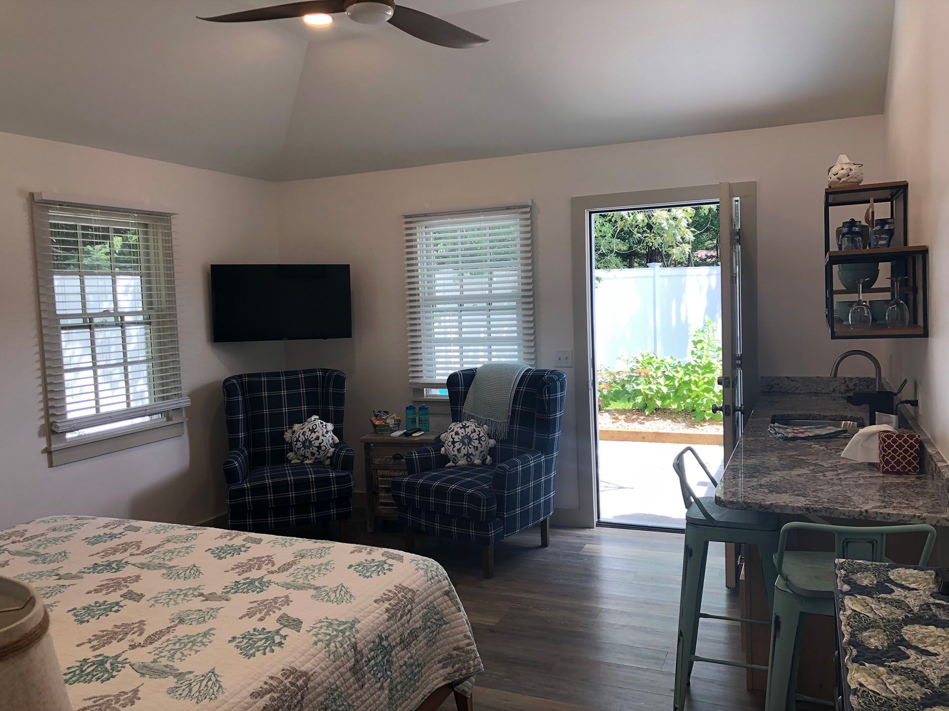 A bedroom with a bed, chairs, television , and a ceiling fan.