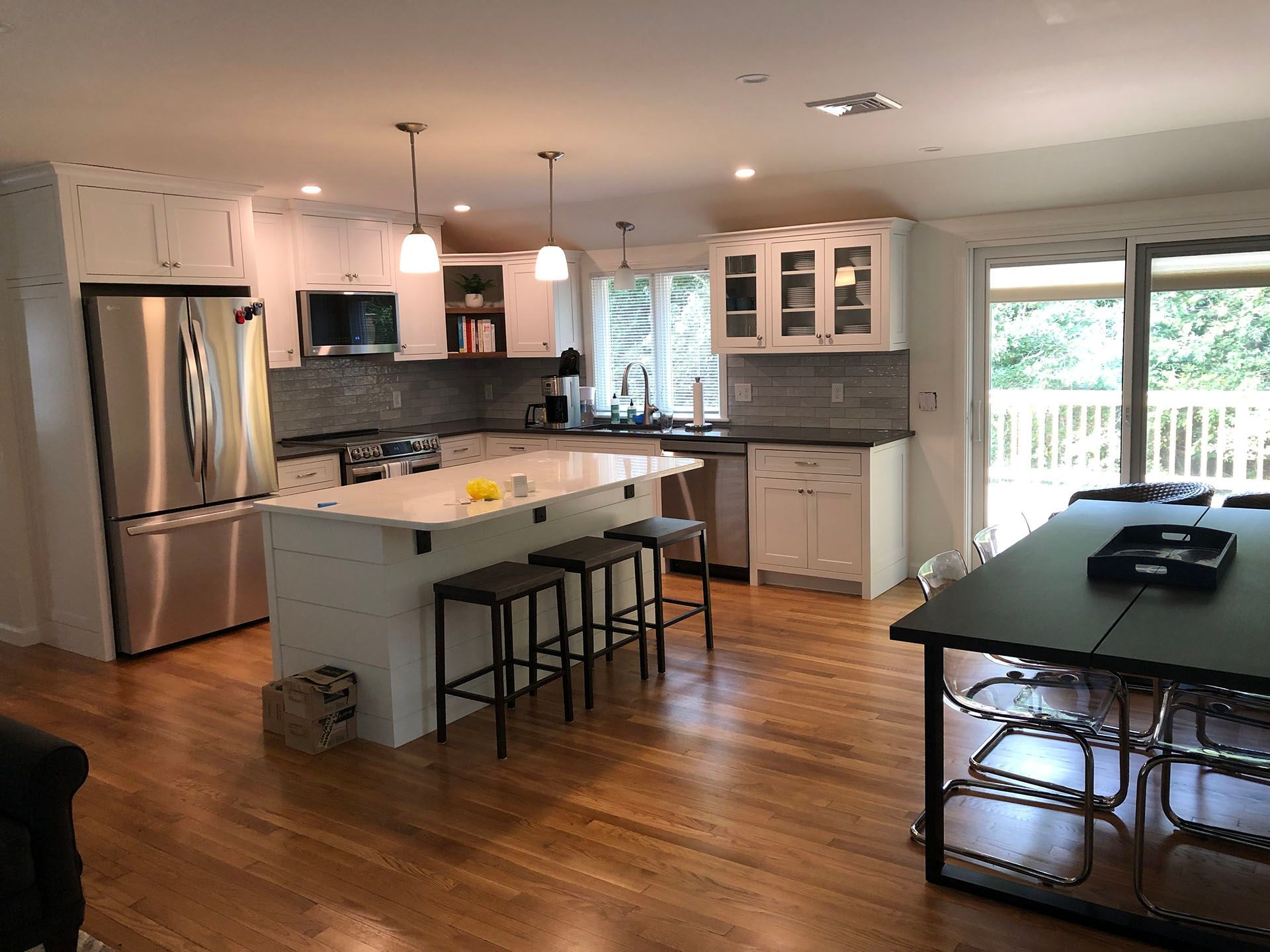 Af finished remodeling kitchen with white cabinets, stainless steel appliances, a large island, a table and chairs.