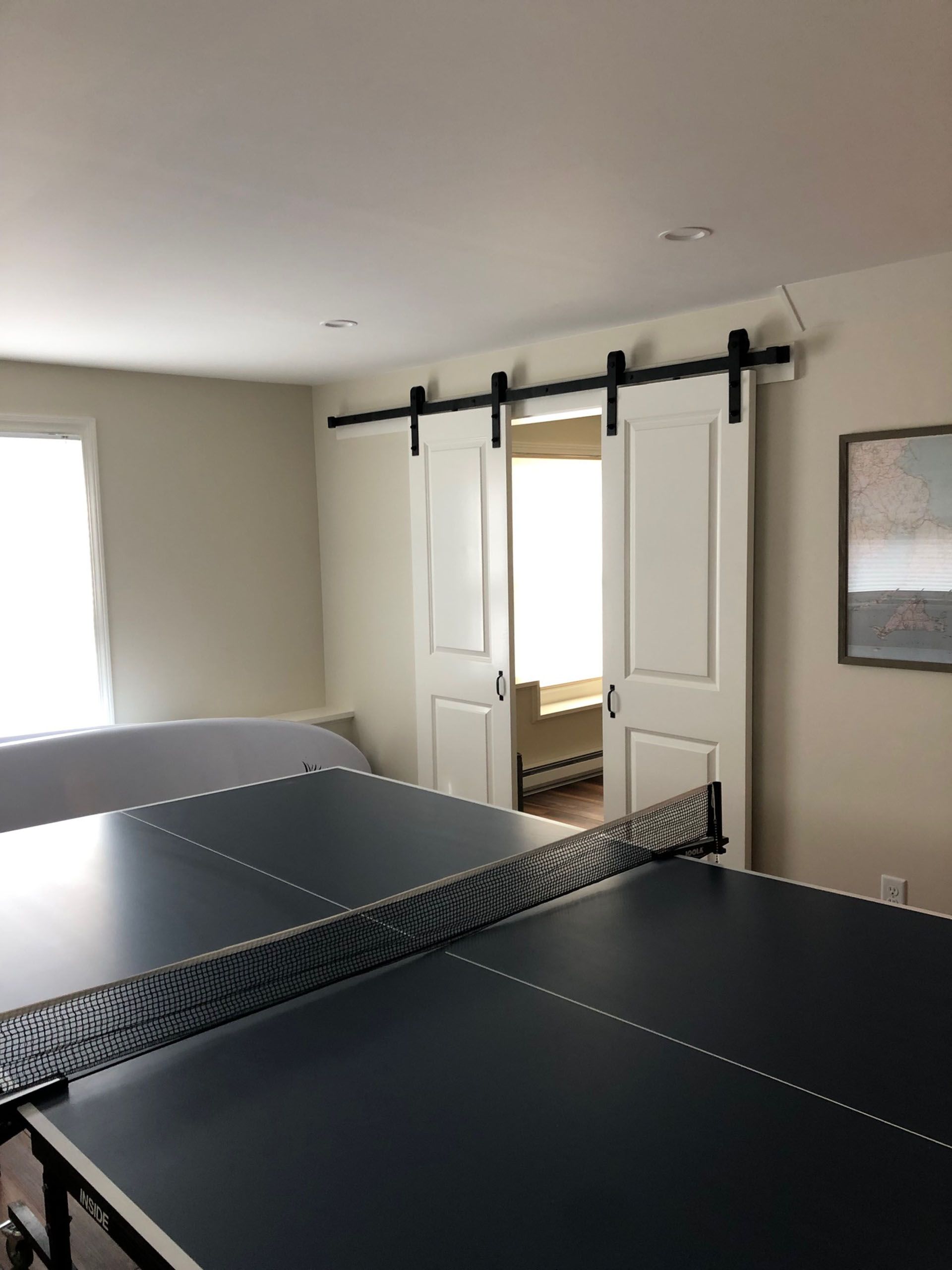 A ping pong table in a room with sliding barn doors.