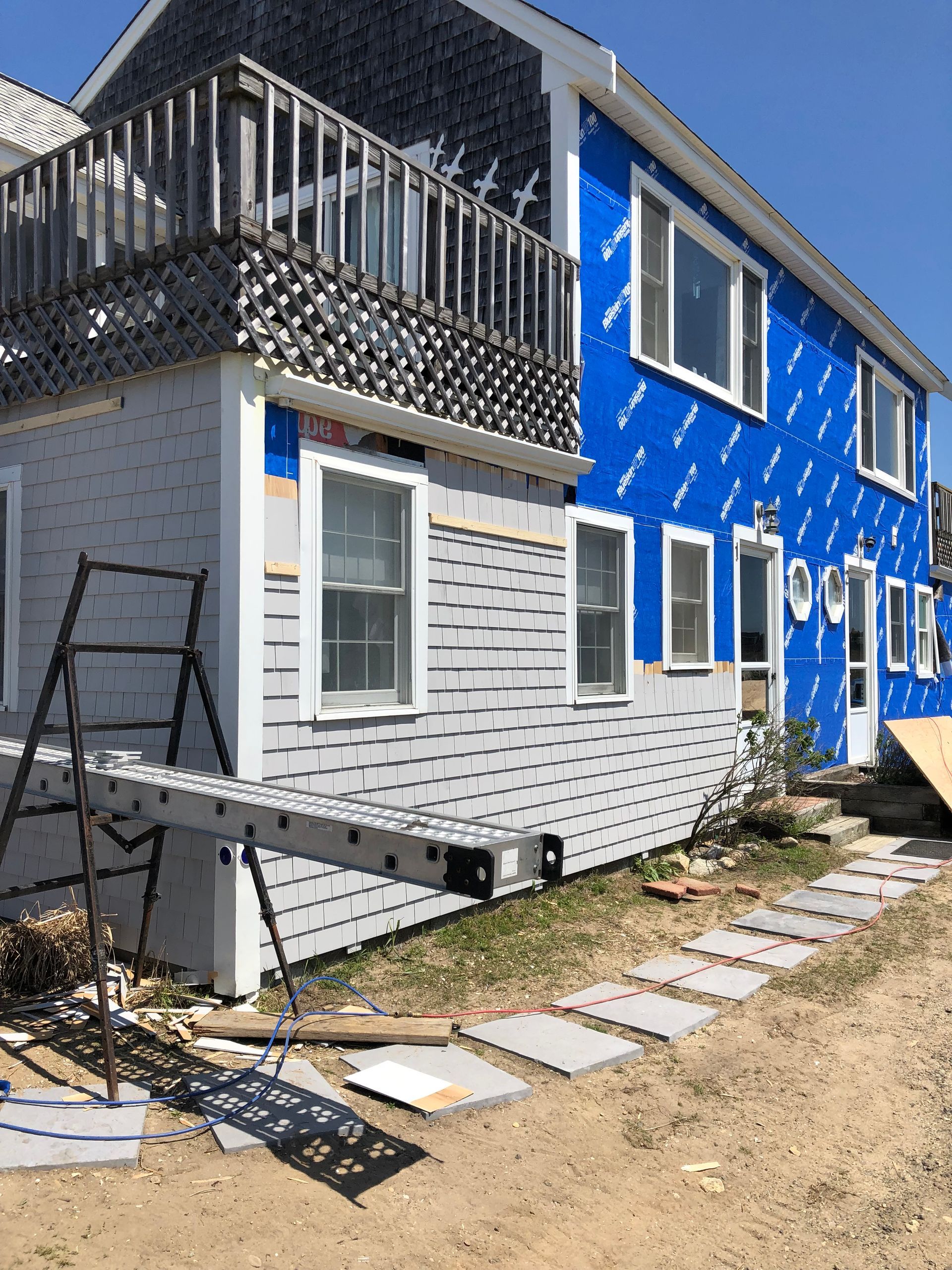 A blue and white house with a ladder in front of it.