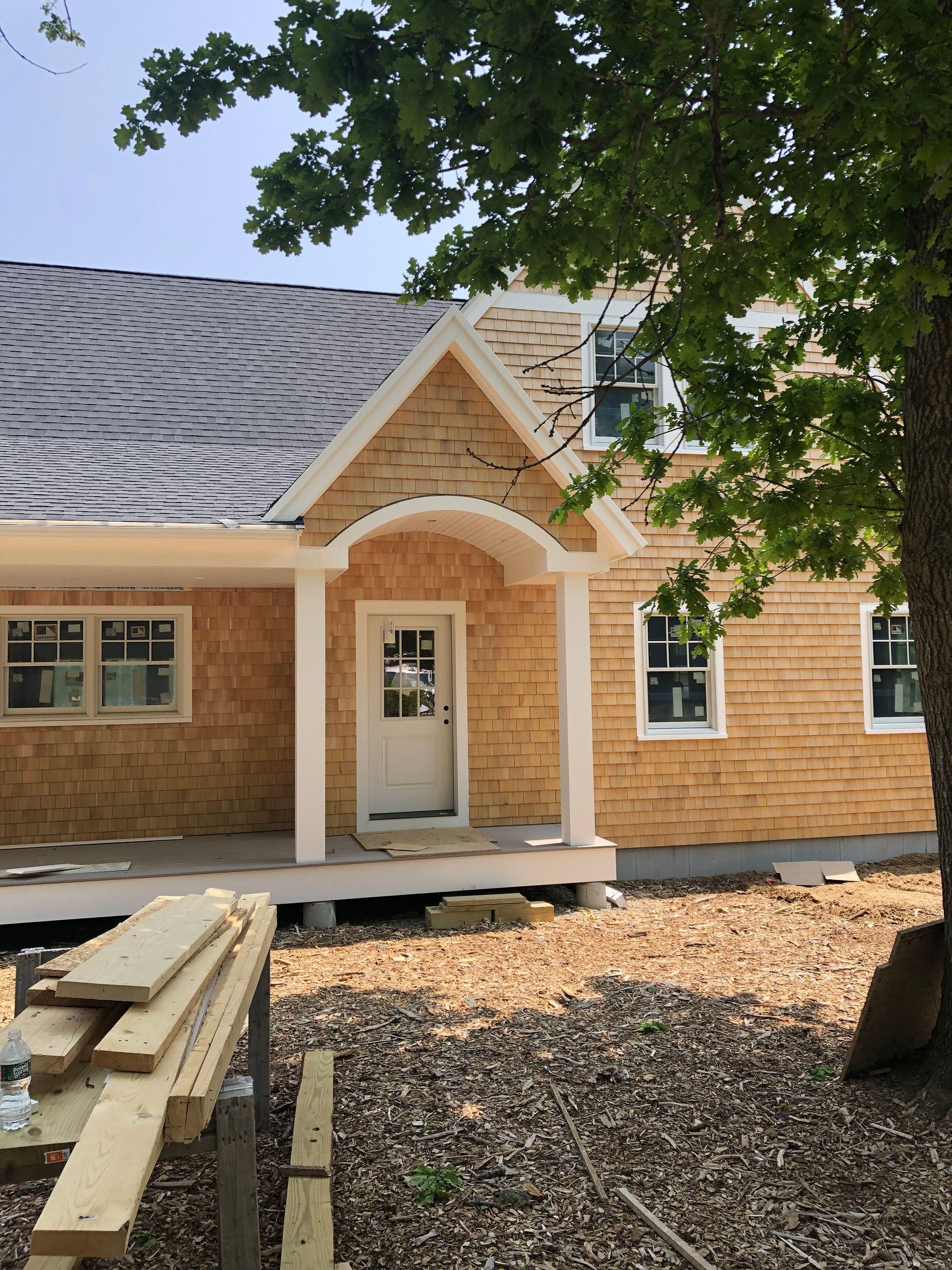 A house with a porch and a tree in front of it