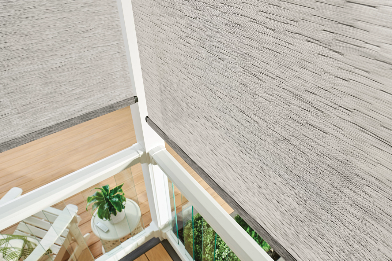 Corner of a bright indoor space with beige blinds, white framing, and a small potted plant below.