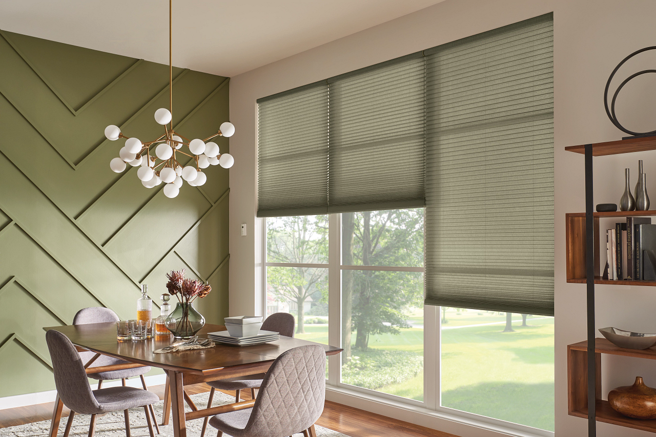 Modern dining room with green walls, round table, chairs, pendant light, and large windows with blinds