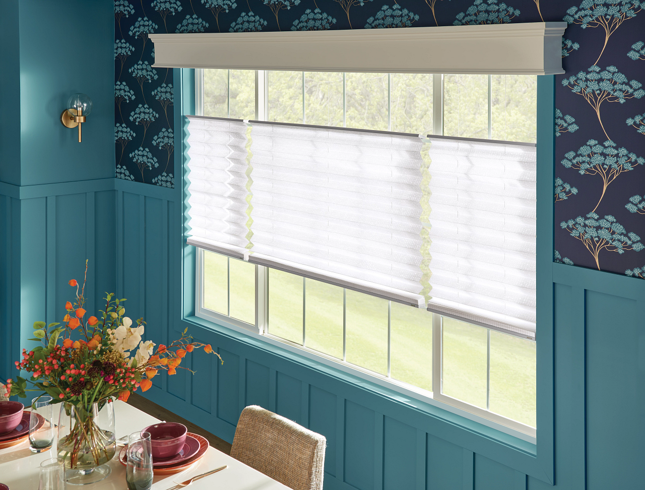 Teal dining nook with floral wallpaper, white blinds, and a table set with flowers and plates
