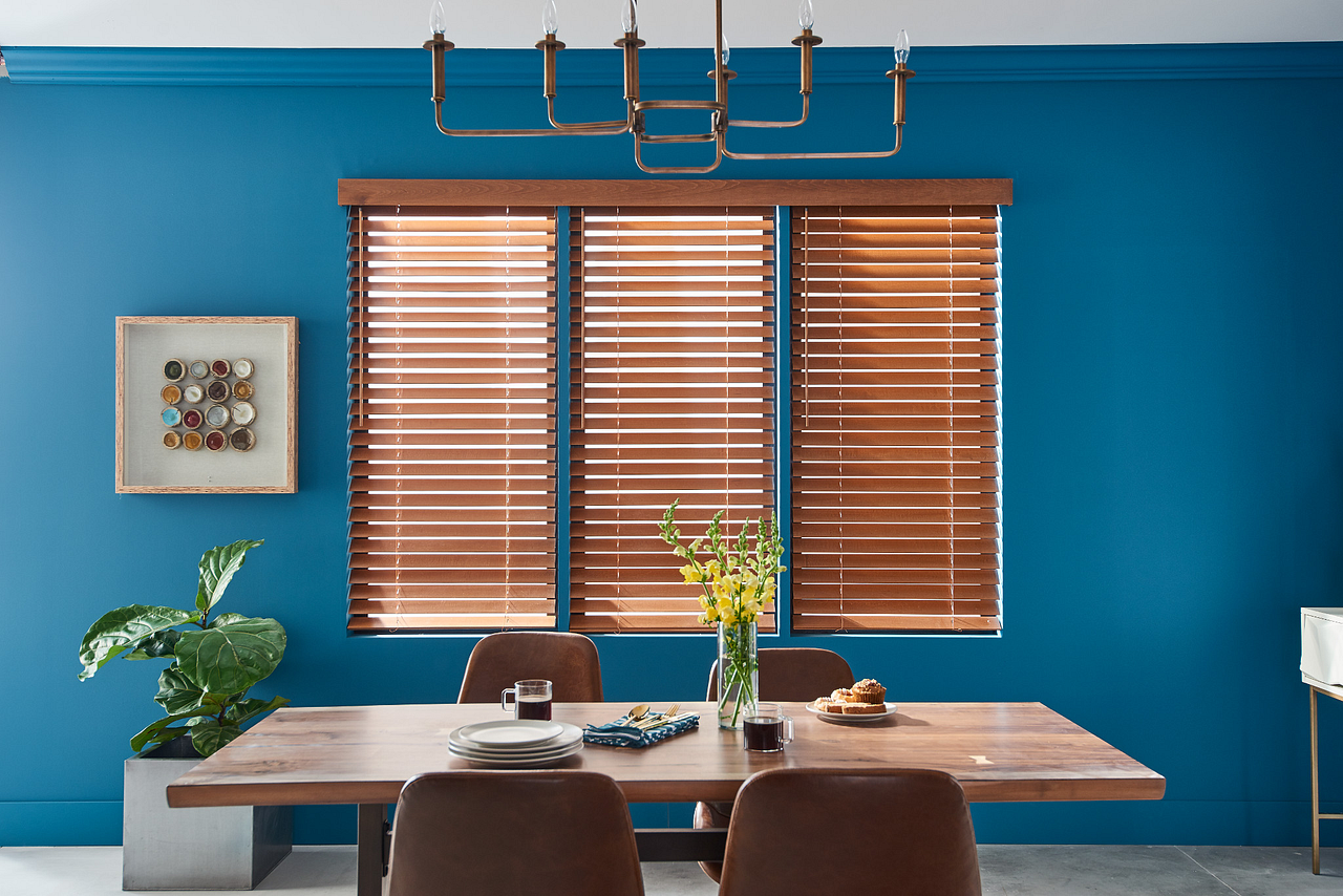 Modern dining room with teal walls, wood blinds, a table, chairs, and a ceiling light fixture