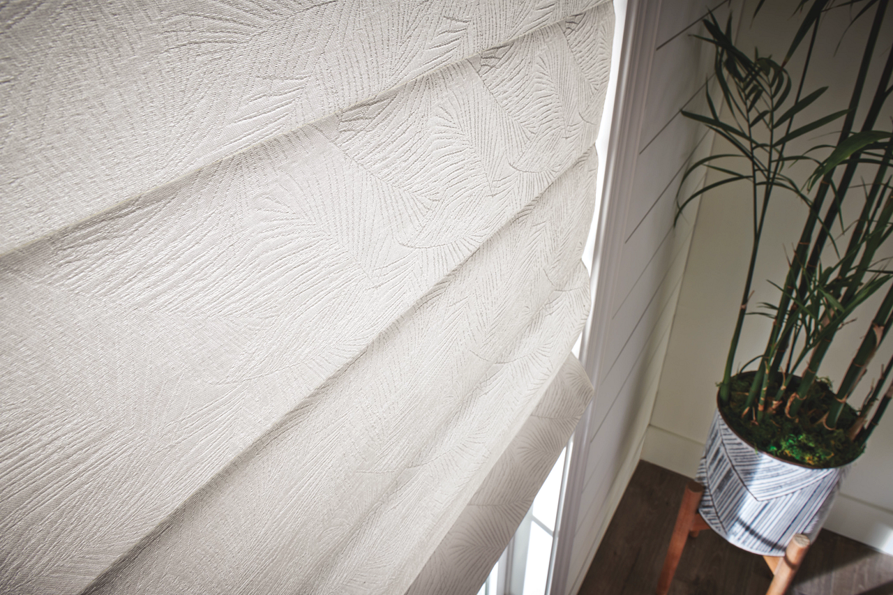 White textured window shade beside a potted plant on a hardwood floor