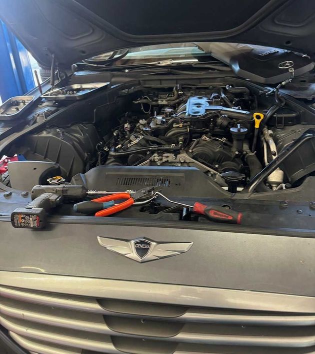 Car engine bay open with tools on the bumper.