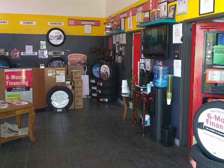 Interior of a tire shop with a waiting area, tires, and signage.