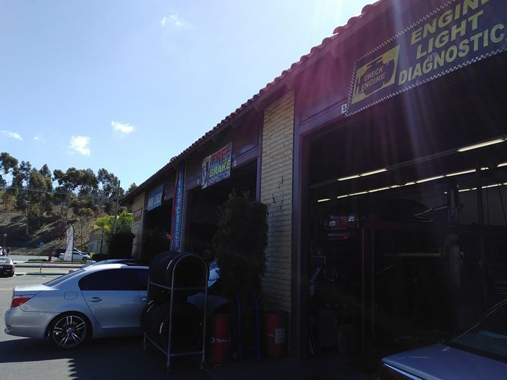 Auto repair shop exterior with open bays, cars, and diagnostic sign.