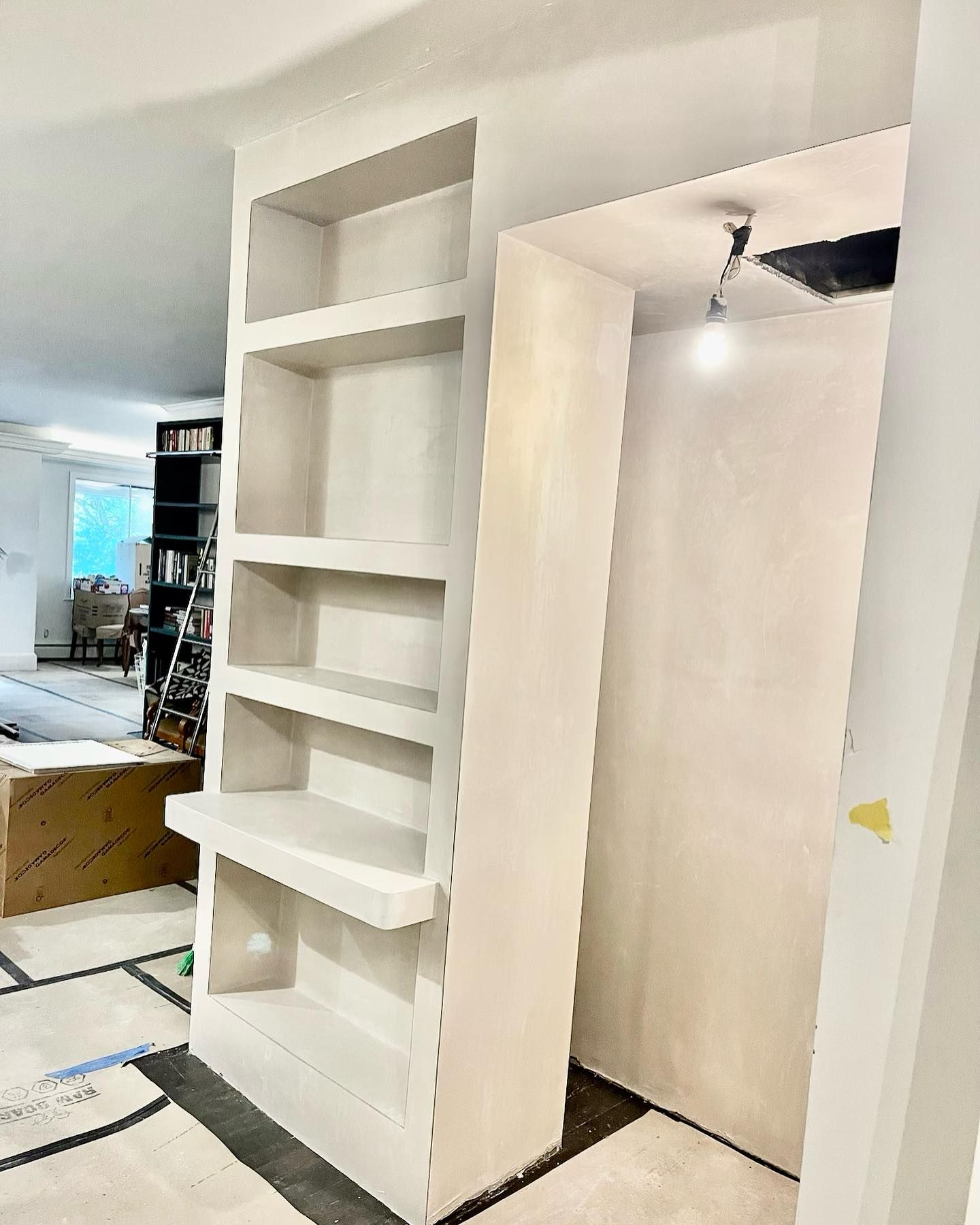 Built-in bookshelf and doorway with a light fixture; construction setting.