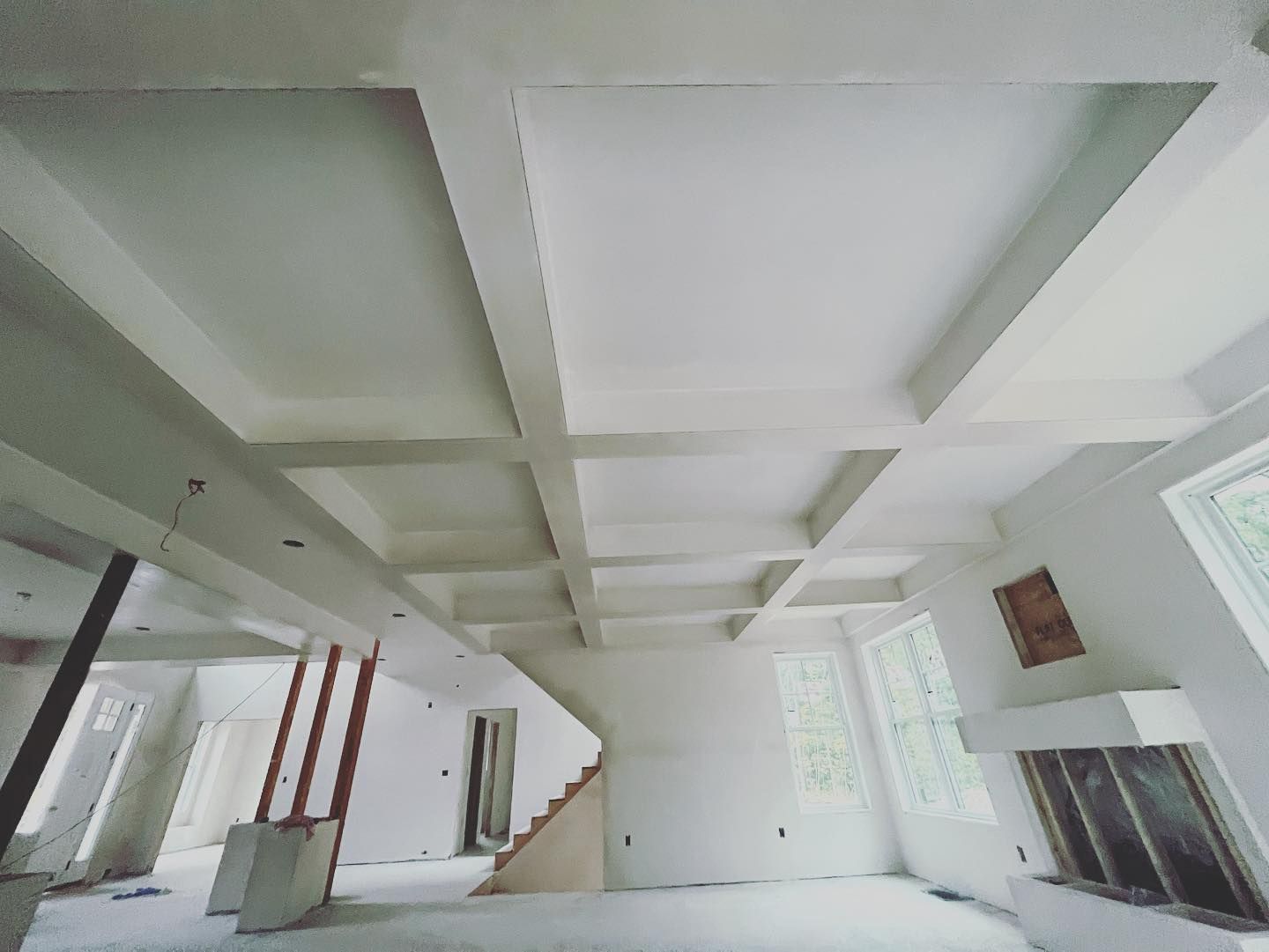 Newly constructed room with white coffered ceiling and unfinished walls.