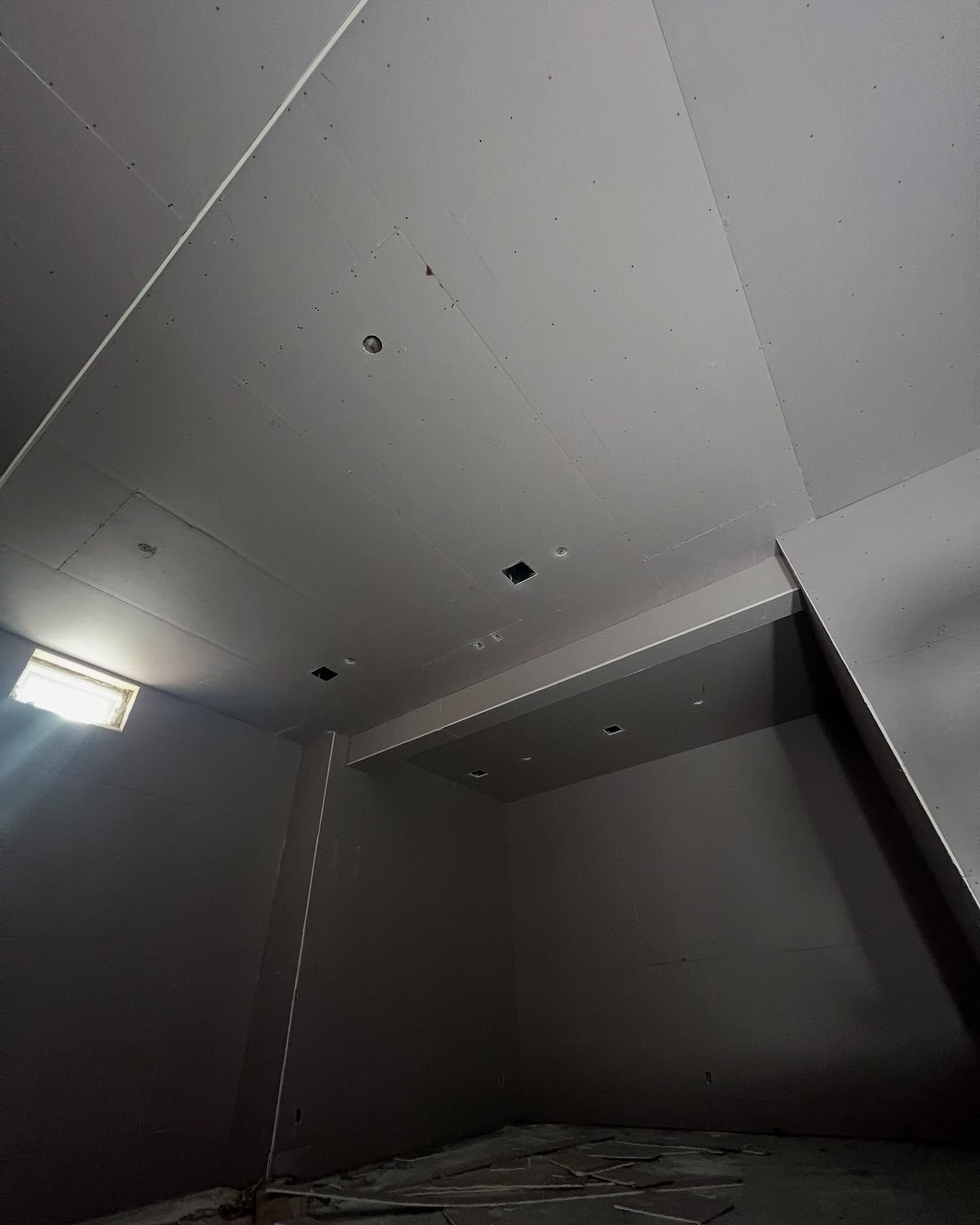 Empty room, gray walls and ceiling, light from a small window.