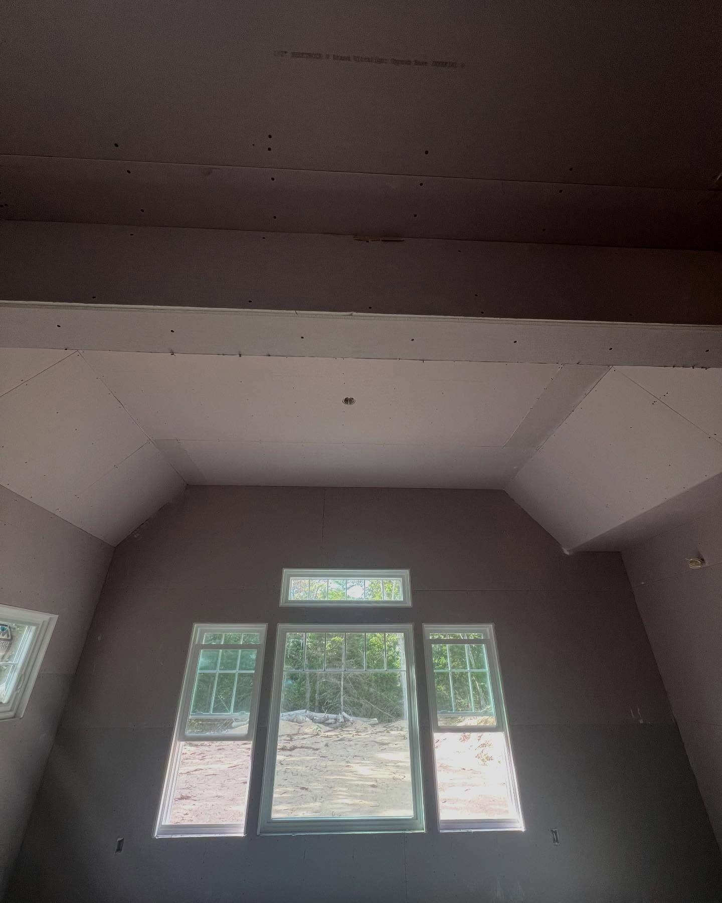 Interior view of a room with pink walls, several windows, and exposed beams.