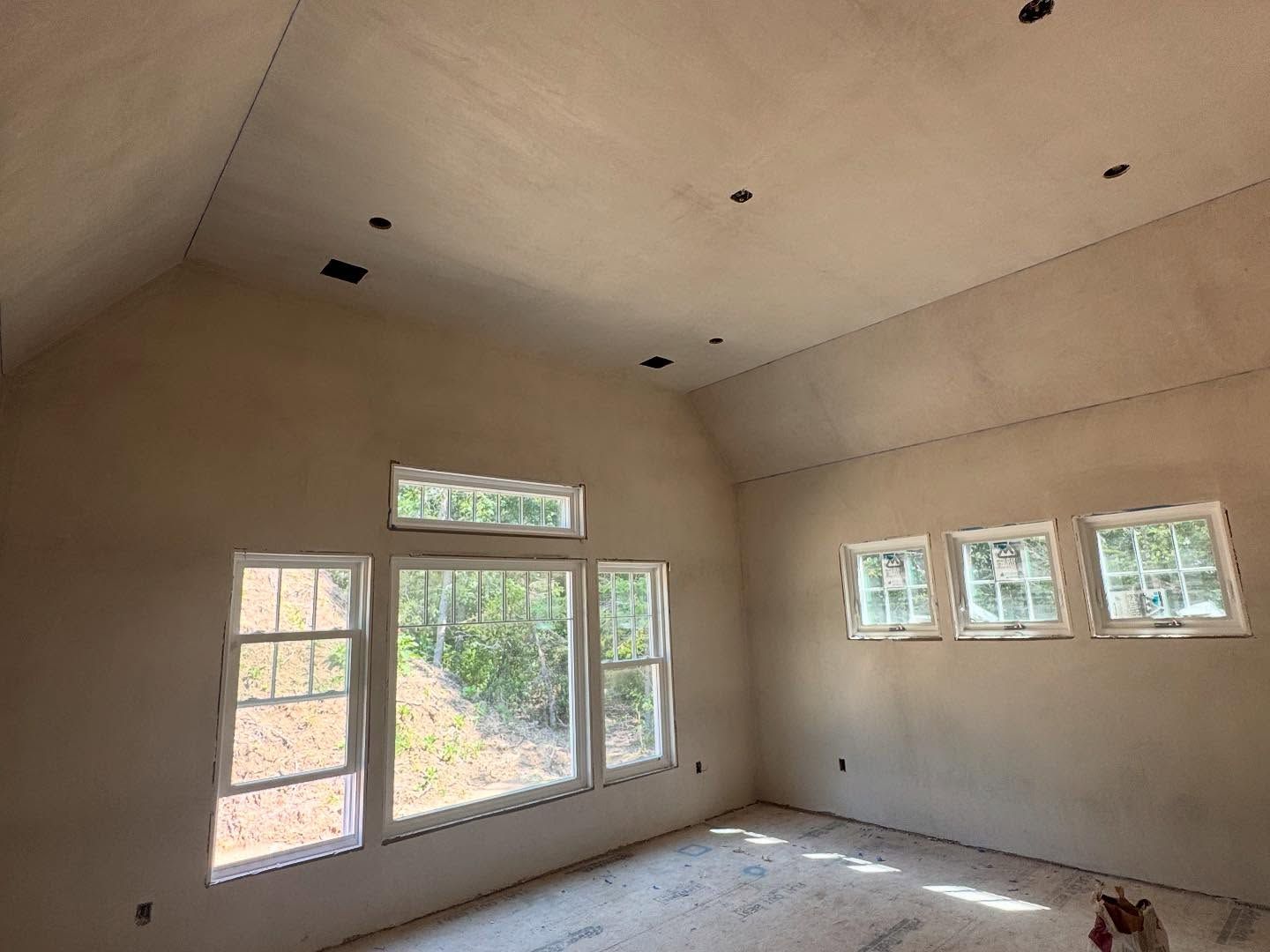 Interior of a room under construction with windows and unfinished walls.