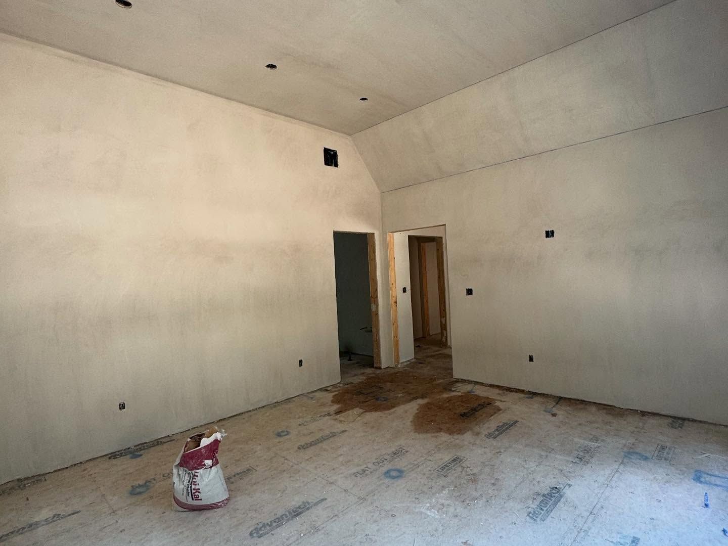 Empty room with gray walls, open doorway, and a bag on the floor.