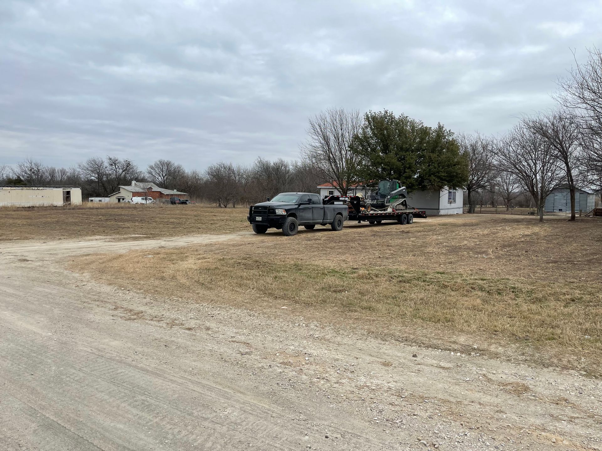 Two trucks are parked on the side of a dirt road.