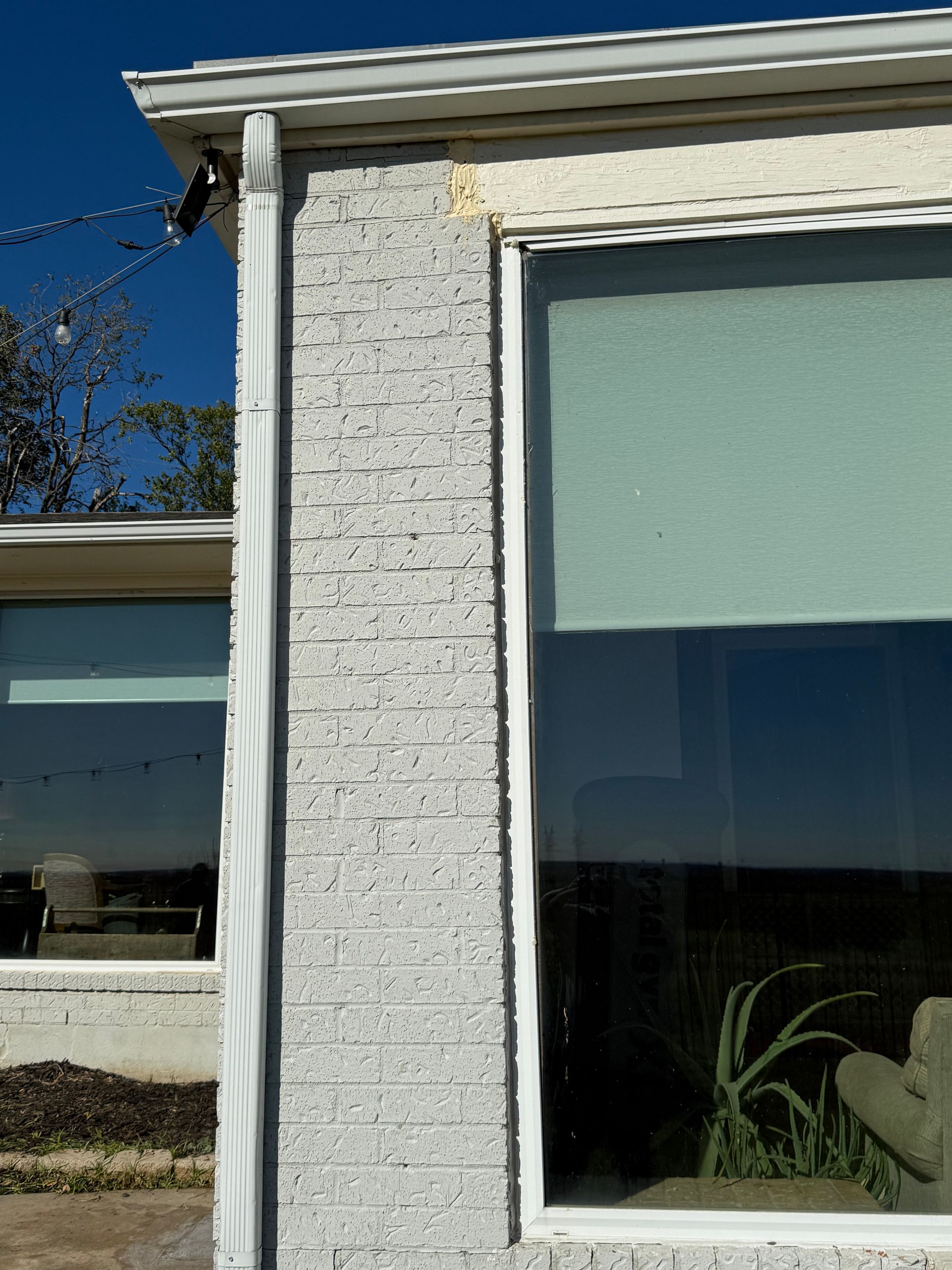 A white brick house with a white window and a white gutter