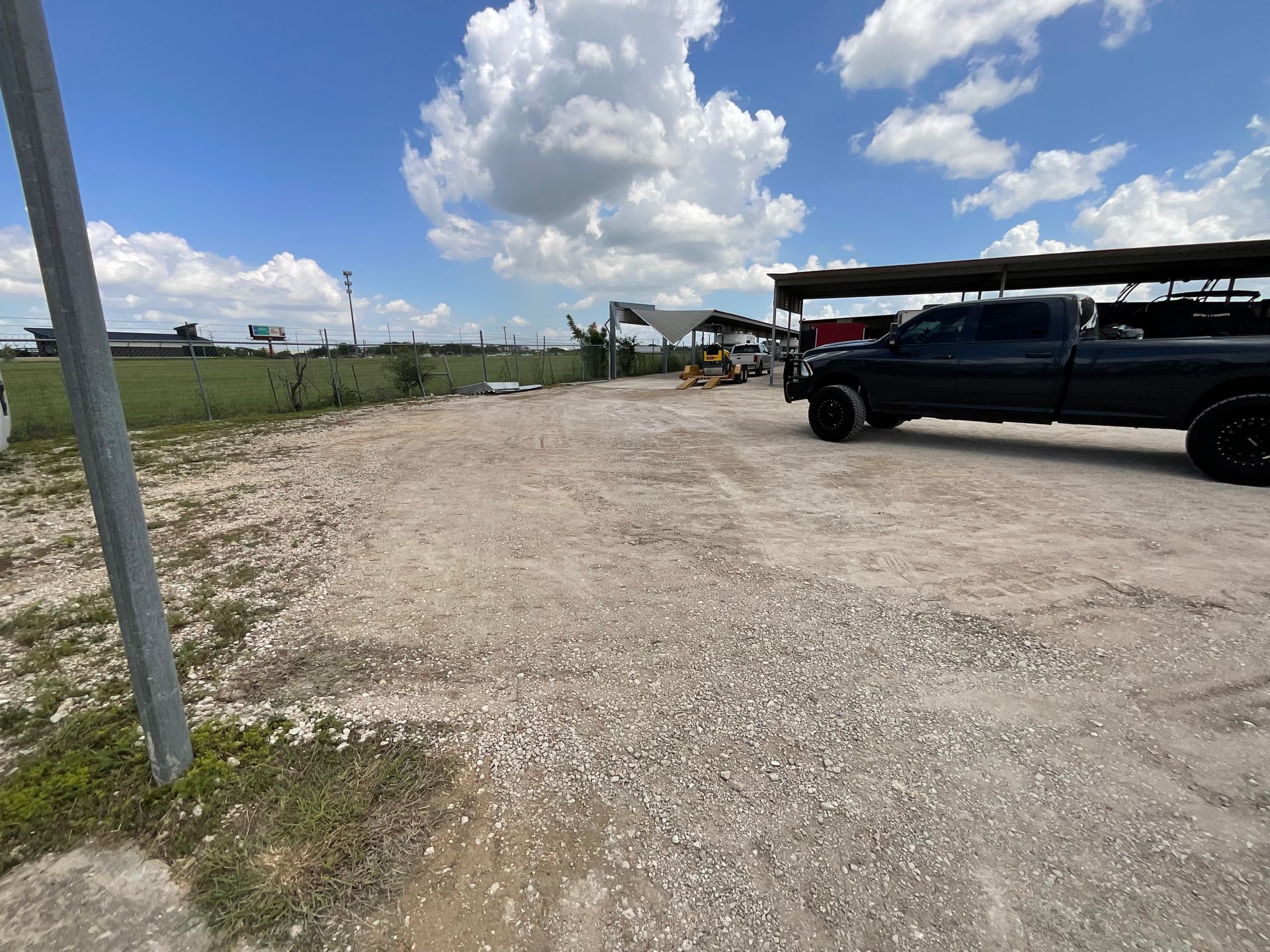 A black truck is parked in a gravel lot.