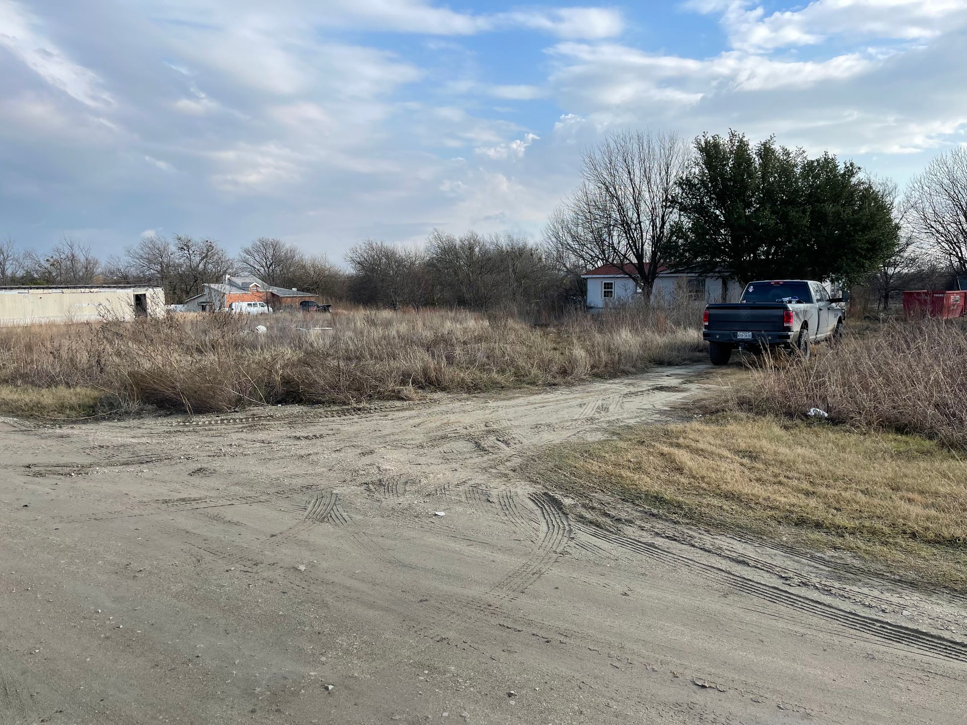 A blue truck is parked on the side of a dirt road.