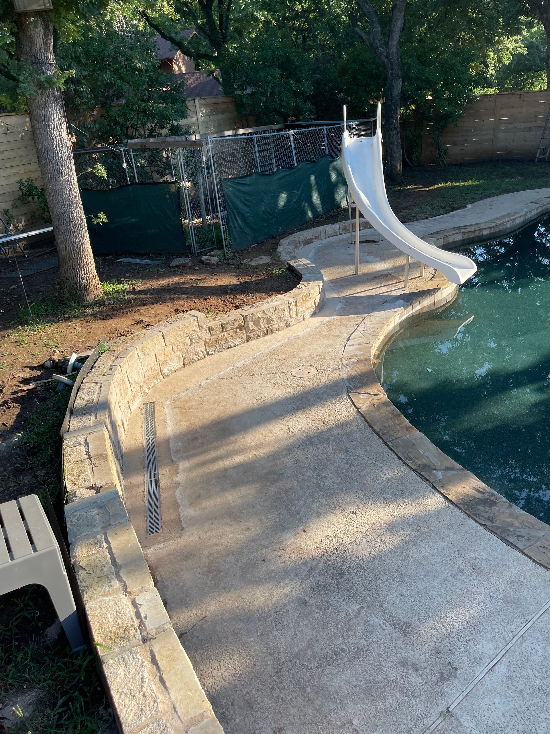 A white slide is sitting next to a swimming pool.