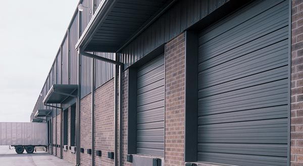A row of garage doors on the side of a brick building.