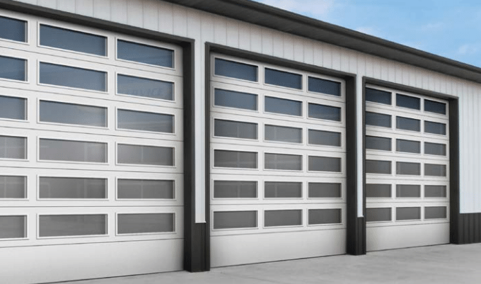 A row of white garage doors on a building with a blue sky in the background.